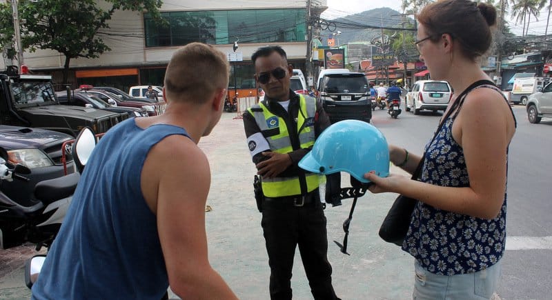 A rider being checked by a traffic police for not wearing the helmet while riding a motorbike in Phuket