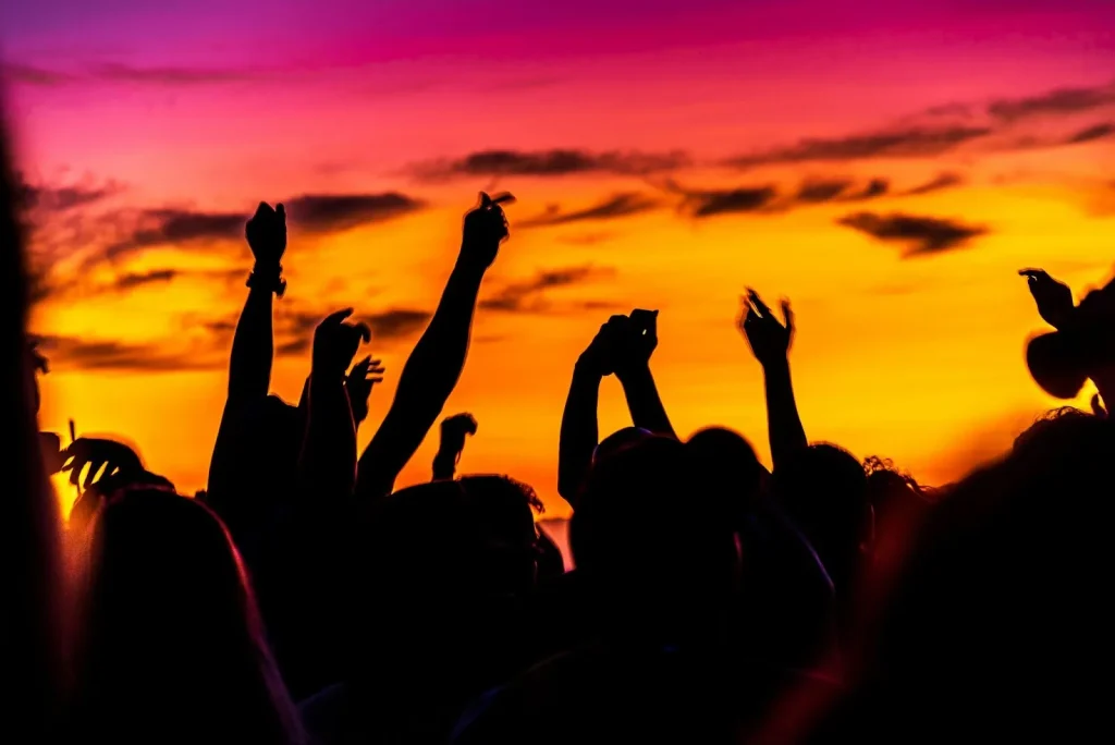 A group of people raising their hands up across the sunset while partying at Koh Lanta Island