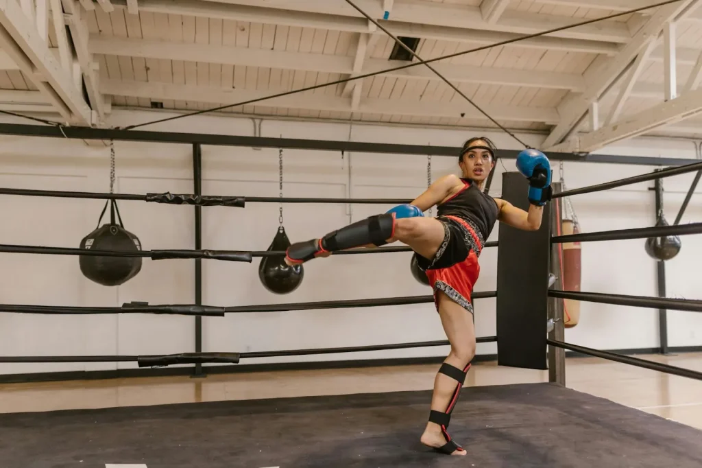 A woman in a high-kick stance inside the boxing ring