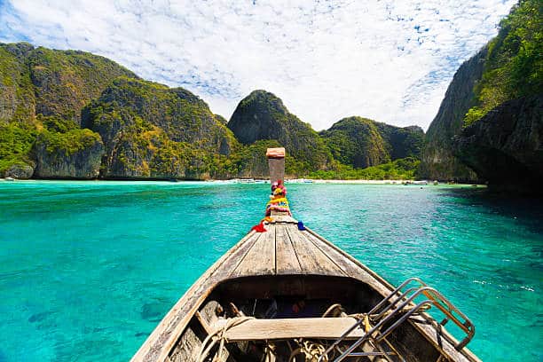 Traditional wooden boats in a picture perfect tropical Maya bay on Koh Phi Phi Island, Thailand, Asia.Traditional wooden boat in a picture perfect tropical bay on Koh Phi Phi Island, Thailand, Asia. The peak travel season on Koh Lanta