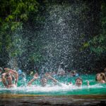 Three boys splashing water in the Emerald Pool in Krabi