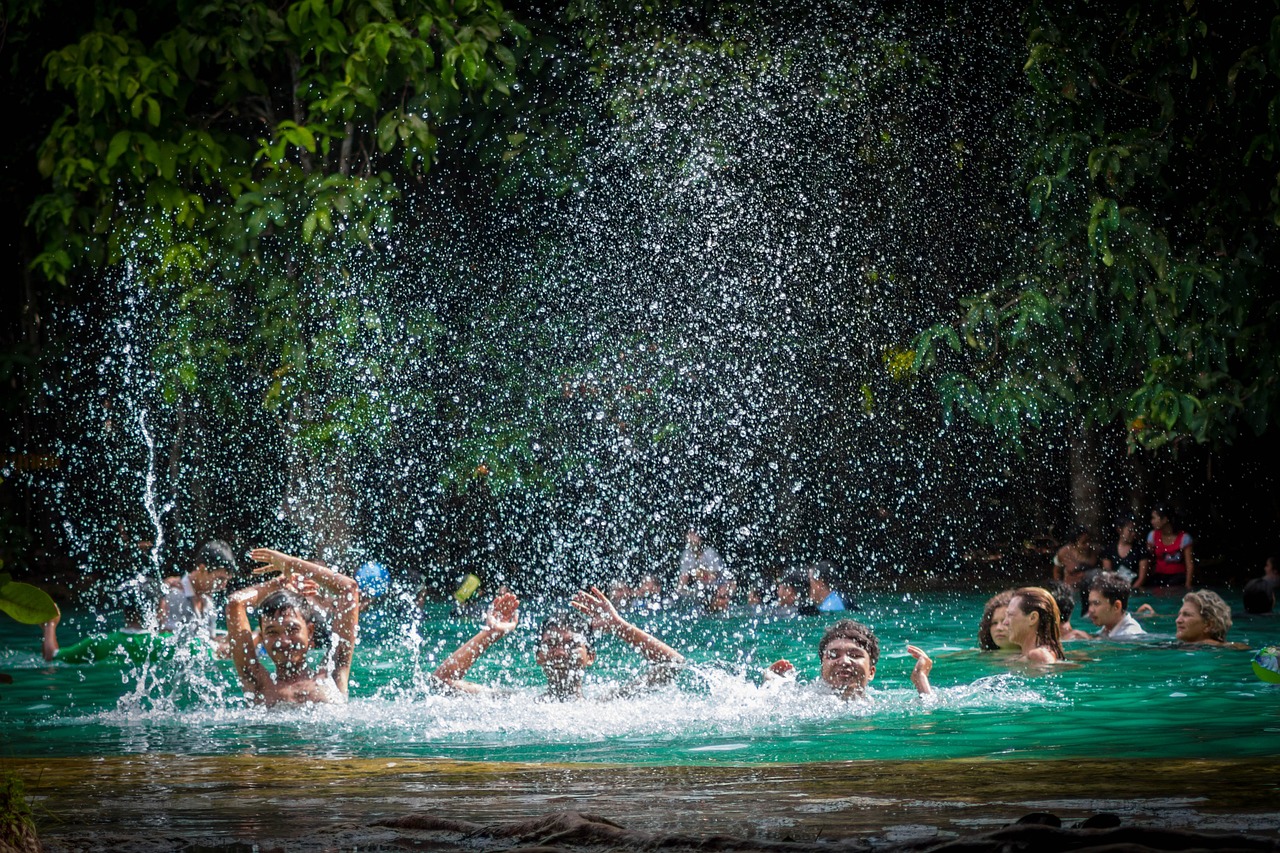 Three boys splashing water in the Emerald Pool in Krabi