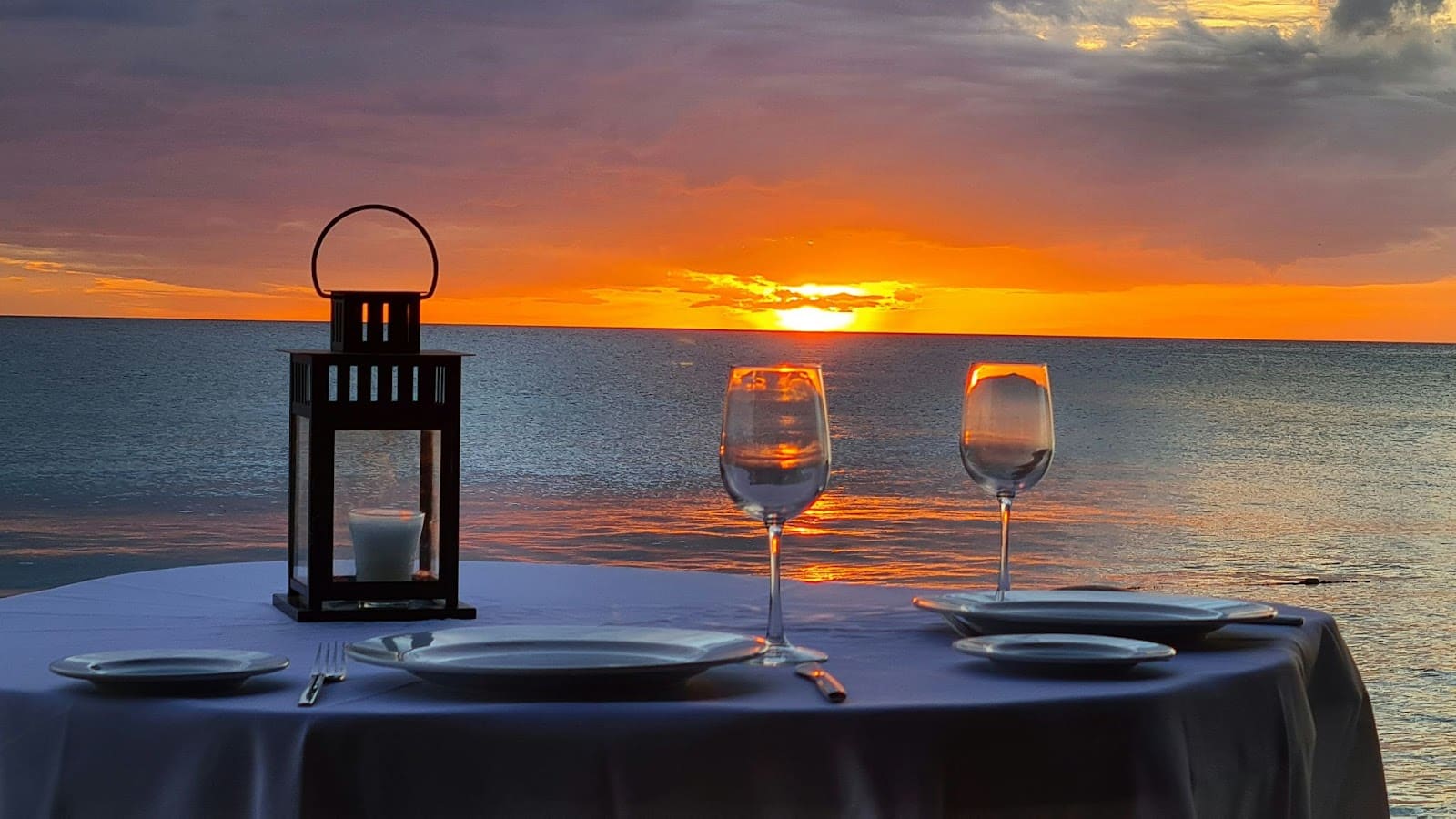 A dinner setting with a sunset view over the ocean.